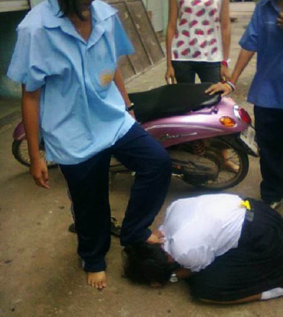 ภาพเด็กนักเรียนก้มกราบ และ อีกคนเอาเท้าเหยียบหัวไว้ ที่มาภาพ: httpnews.mthai.comgeneral-news167163.html