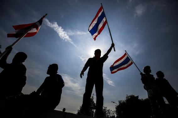Anti-government protesters wave flags after they toppled barricades near the Government House in Bangkok ที่มาภาพ : http://s1.reutersmedia.net