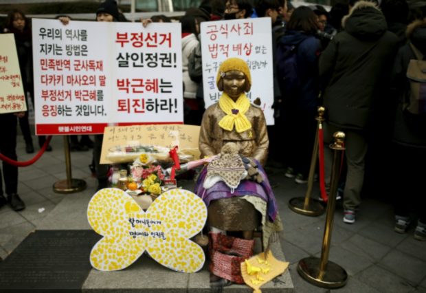 รูปของหญิงสาวคนหนึ่งที่ตกเป็นเหยื่อทางเพศโดยทหารญี่ปุ่น ตั้งอยู๋ด้านหน้าของสถานทูตญี่ปุ่นในกรุงโซล เกาหลีใต้ ในช่วงสัปดาห์การชุมนุมต่อต้านญี่ปุ่น เมื่อวันที่ 30 ธันวาคม 2015 ที่มาภาพ : http://www.forbes.com/sites/scottasnyder/2016/02/01/the-japan-korea-comfort-women-deal-this-is-only-the-beginning/#65ce99bb2e0b